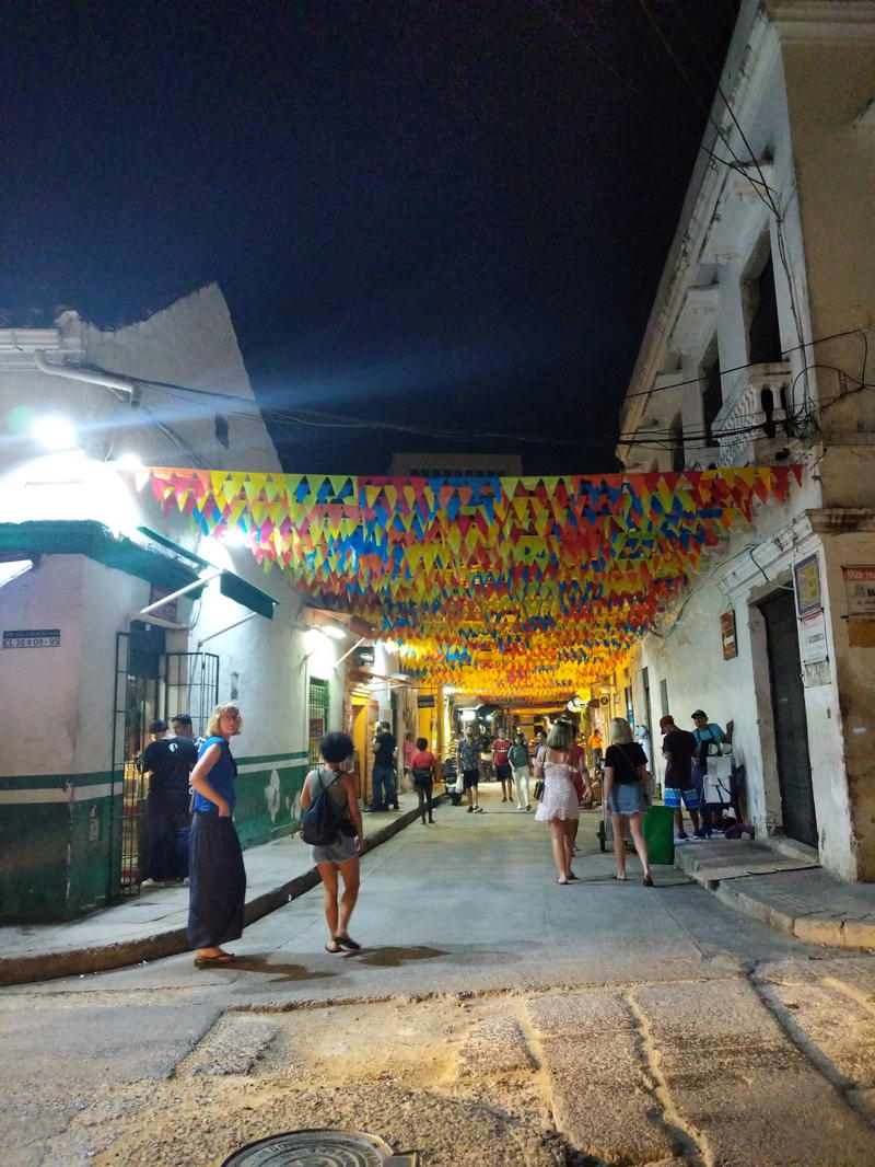 A group of people walking down a street at night.