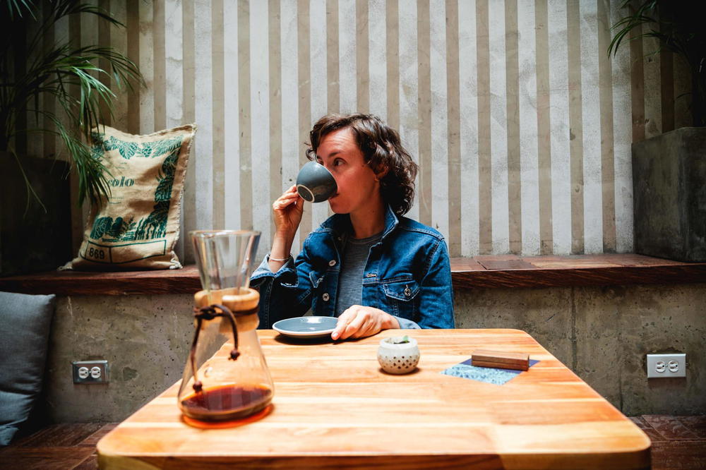 Girl drinking espresso from a cup at a table in a chic coffee shop
