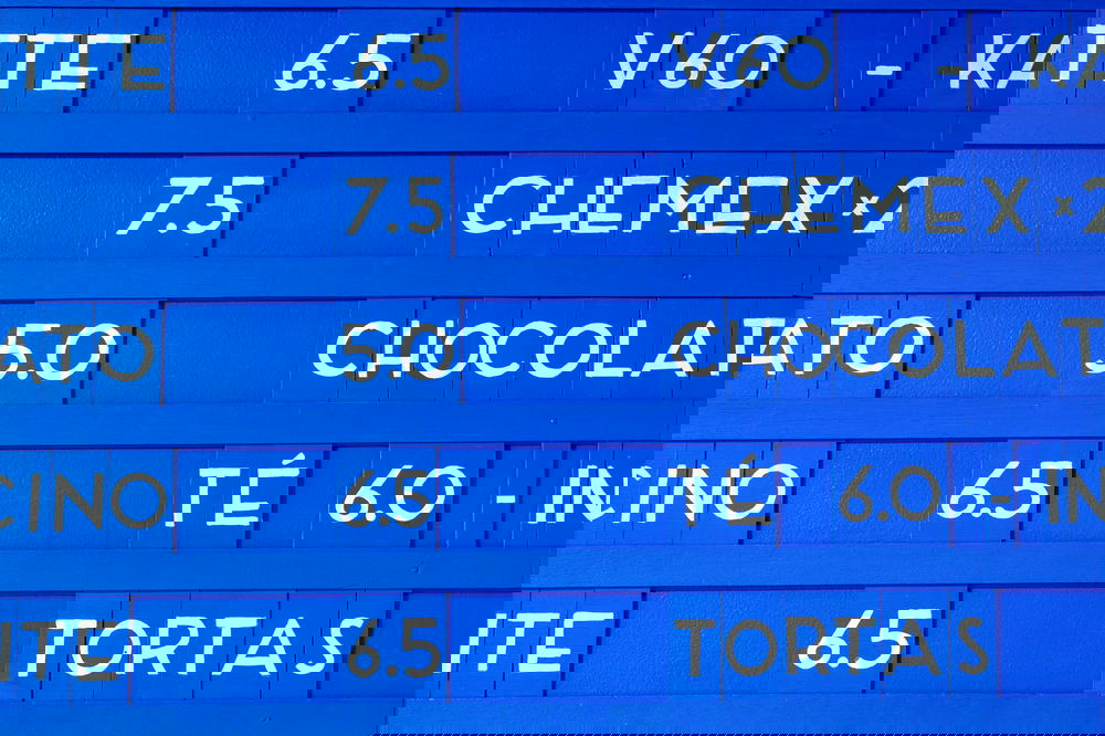 Blue coffee shop text board depicting coffees and prices of the day along a wall