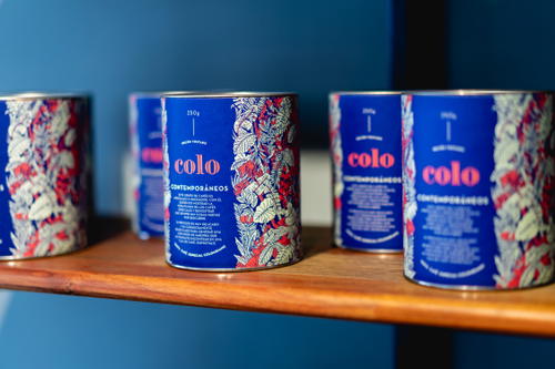 Four cans of cola sitting on a shelf.