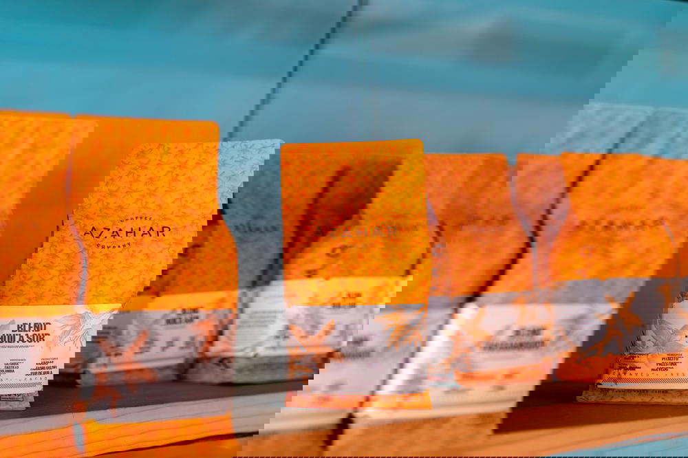 Orange bags of coffee beans for sale against a teal wall at a third wave cafe