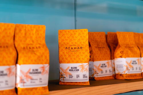 A row of bags of coffee sitting on a shelf.