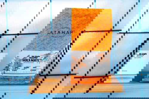 A bag of coffee sits on a shelf next to a business card.