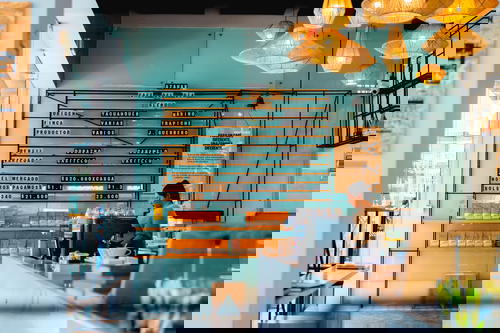 A woman is standing at the counter of a coffee shop.