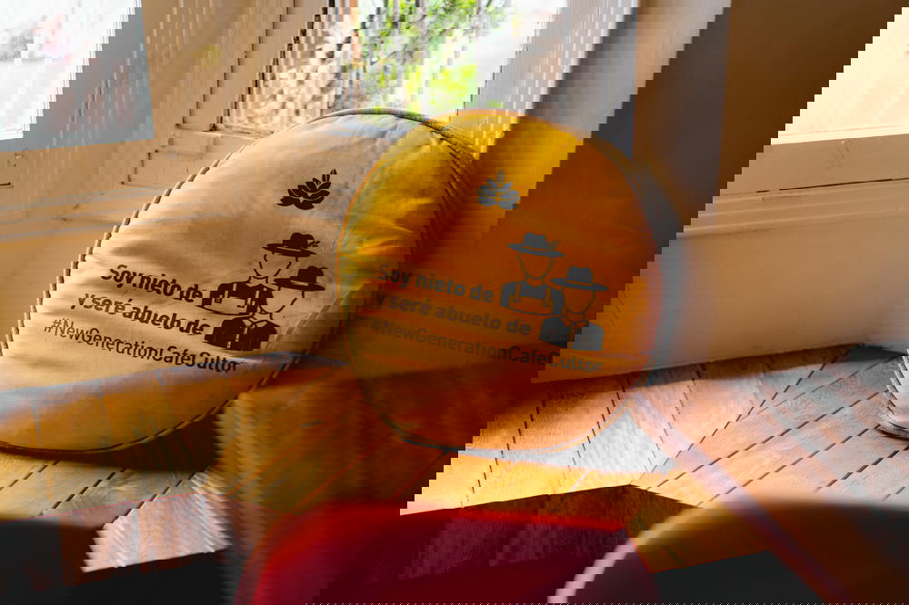 Yellow gold coffee themed Spanish throw pillow in a bay window of a Bogota coffee shop