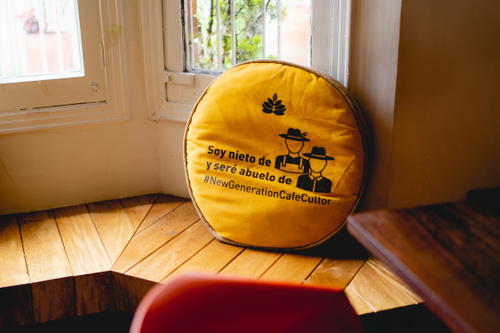 A yellow cushion on a wooden floor next to a window.