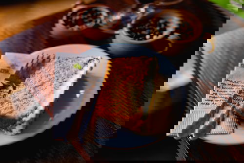 A slice of cake on a plate with a fork and coffee.