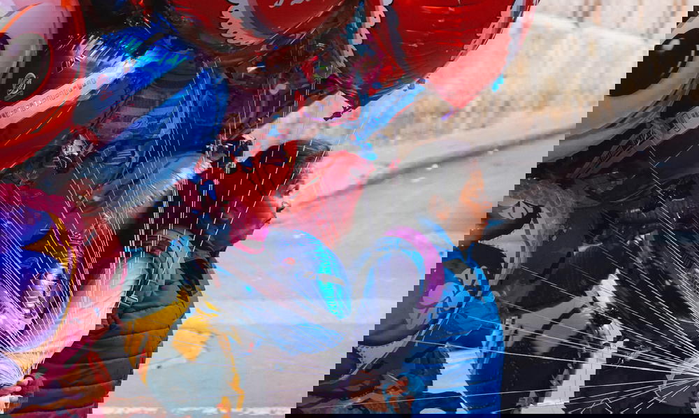 A girl carrying a bunch of balloons.