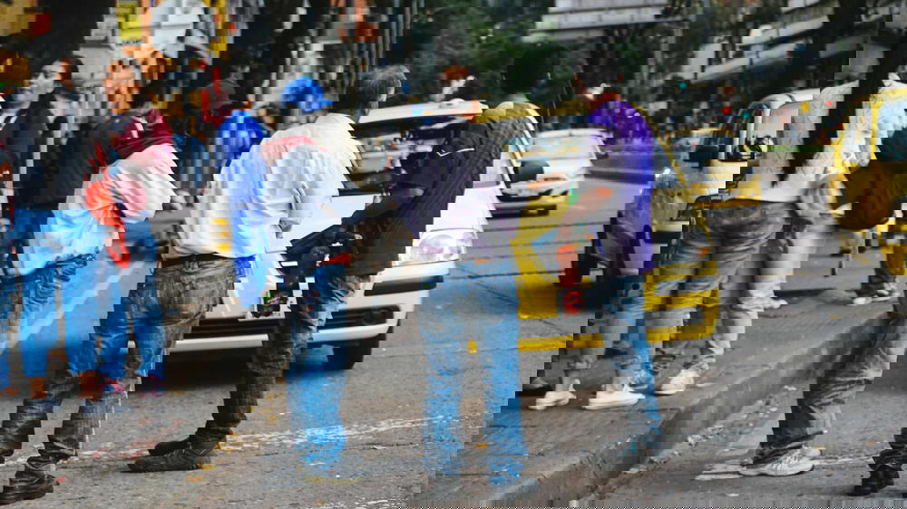 A group of people standing next to a yellow taxi.