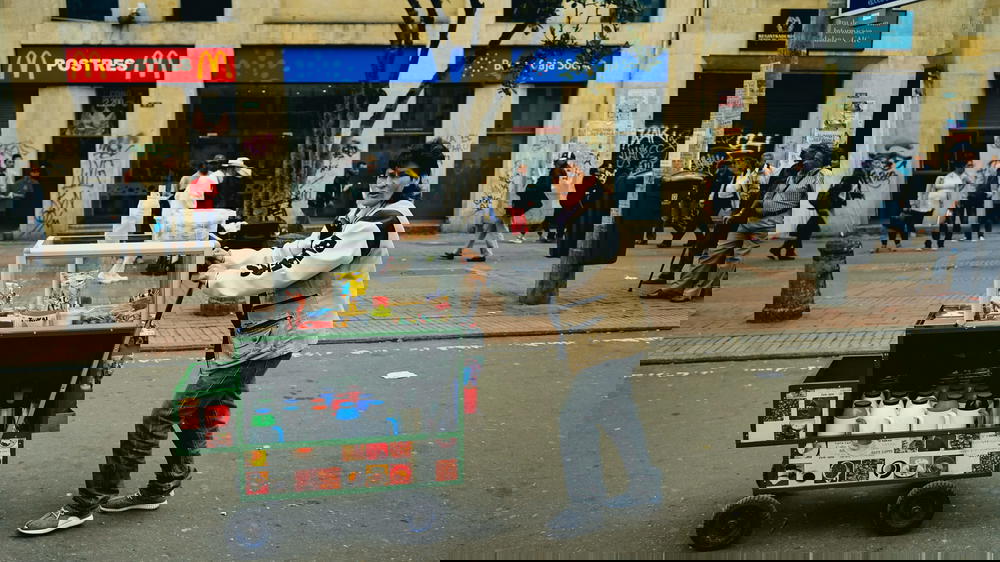 A man pushing a cart on the street.