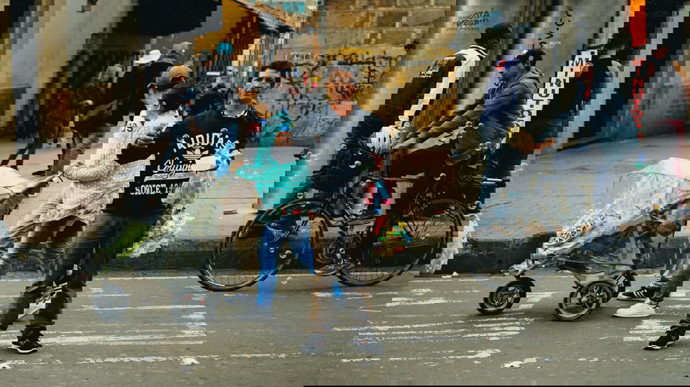 A man standing on a street with a baby stroller.