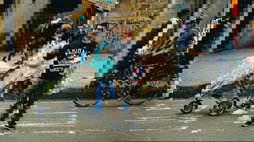 A man standing on a street with a baby stroller.