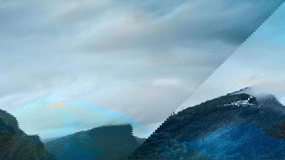 A church on top of a mountain under a cloudy sky.