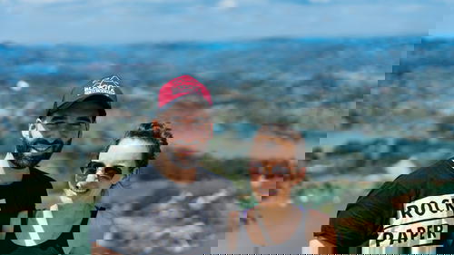 A man and woman posing for a photo on top of a mountain.