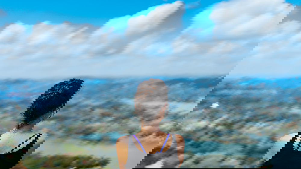 A woman looking out over a lake with mountains in the background.