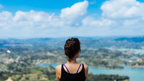 A woman looking out over a lake with mountains in the background.