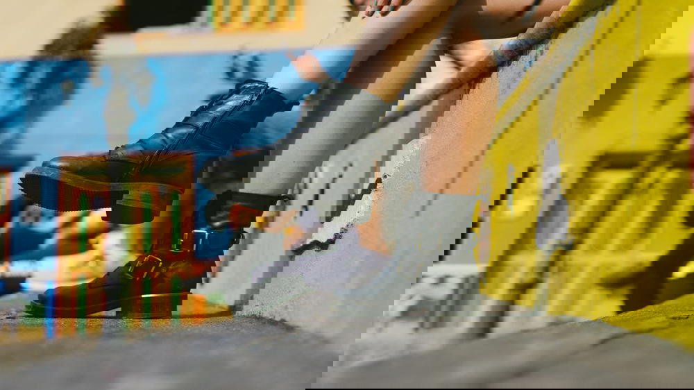 A woman is sitting on a ledge wearing black boots.