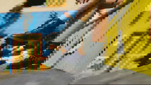 A woman is sitting on a ledge wearing black boots.