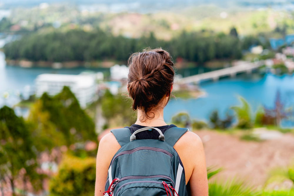 Woman wearing a backpack looking at islands and lakes of Guatape Colombia