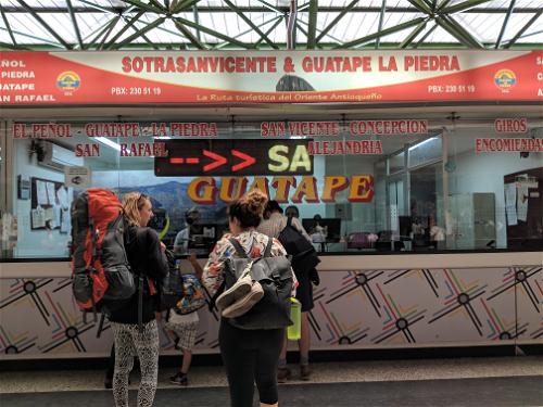 Backpackers buying bus tickets at ticket window for bus from Medellin to Guatape Colombia