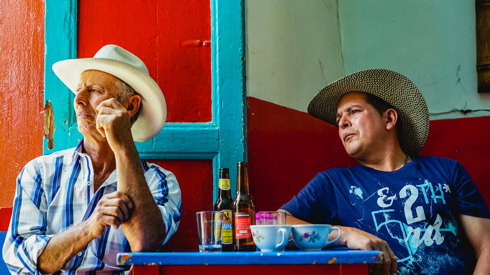 Two men sitting at a table in a colorful building.