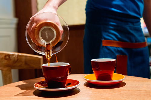 Pouring two cups of coffee from a Chemex in Pergamino cafe