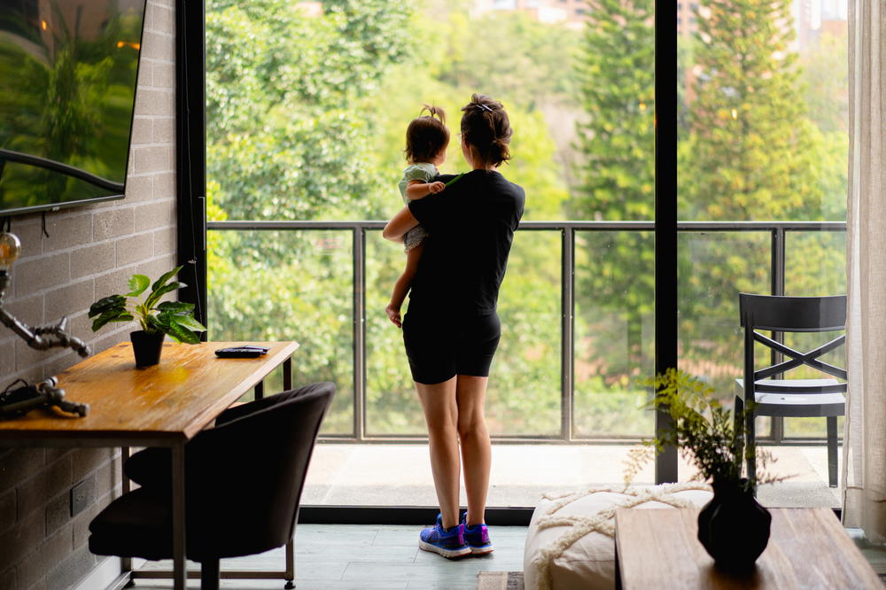 A woman holding a child looking out of a window