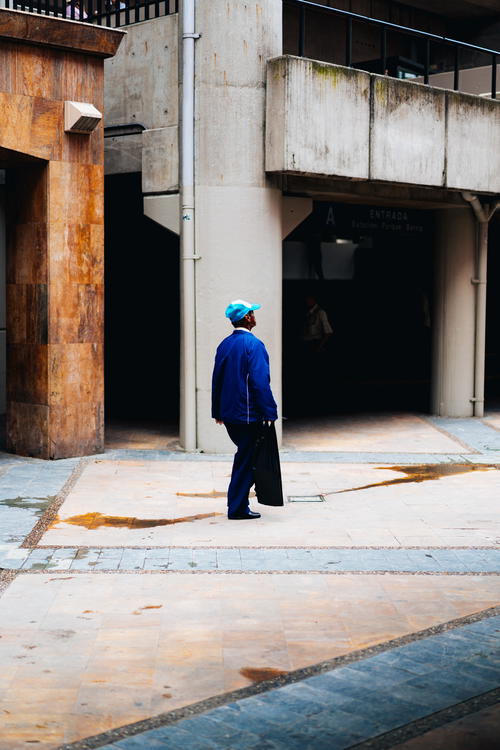 A man in a blue jacket is walking down the street