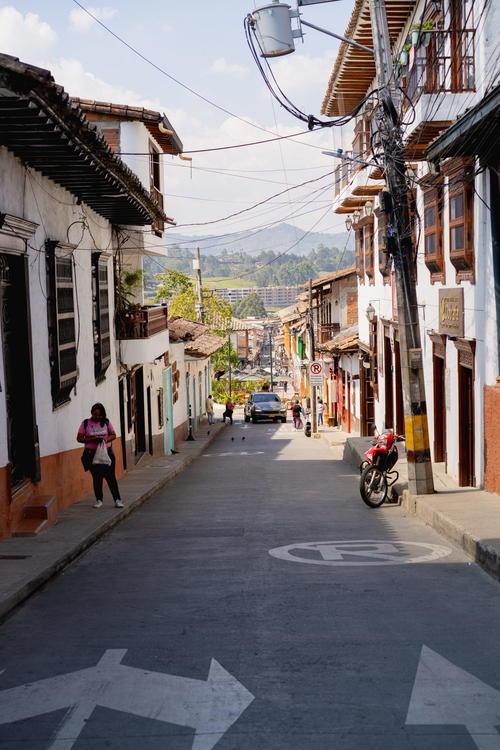 A woman walking down a street next to buildings