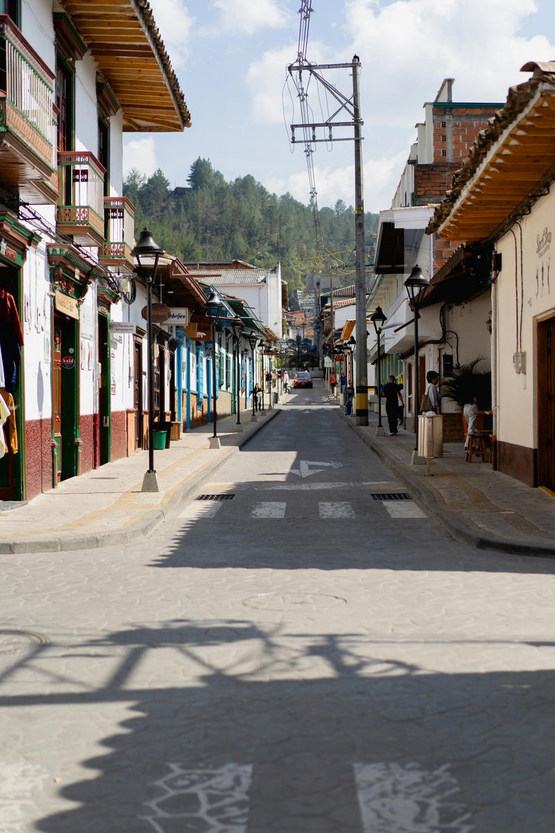 A narrow street with buildings and a clock tower in the distance