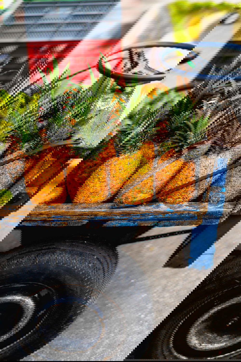 Small painted blue wooden truck full of pineapples for sale