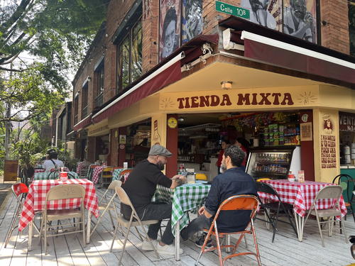 a group of people sitting at tables outside of a restaurant