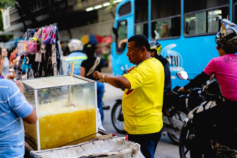 A man selling a drink on a street in a city.