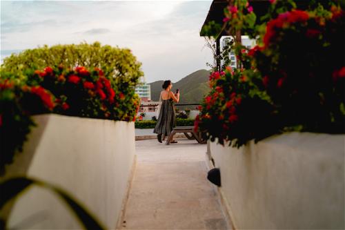 A woman is walking down a walkway with flowers in the background.