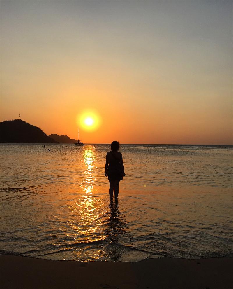 Woman standing in the ocean during sunset