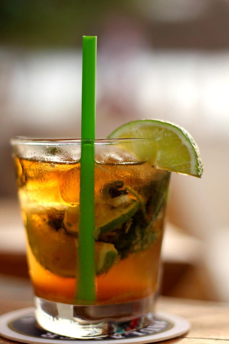 Close-up cold drink with short green straw and a lime wedge