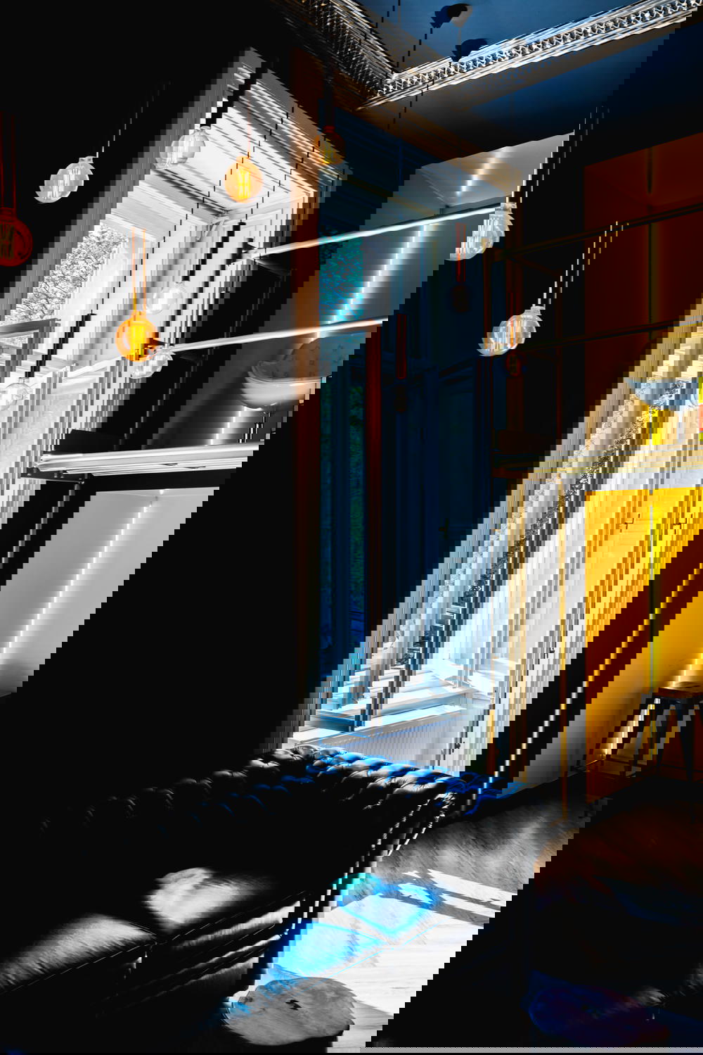 Lights hanging next to an open window and a black leather couch in Meetme23's lobby