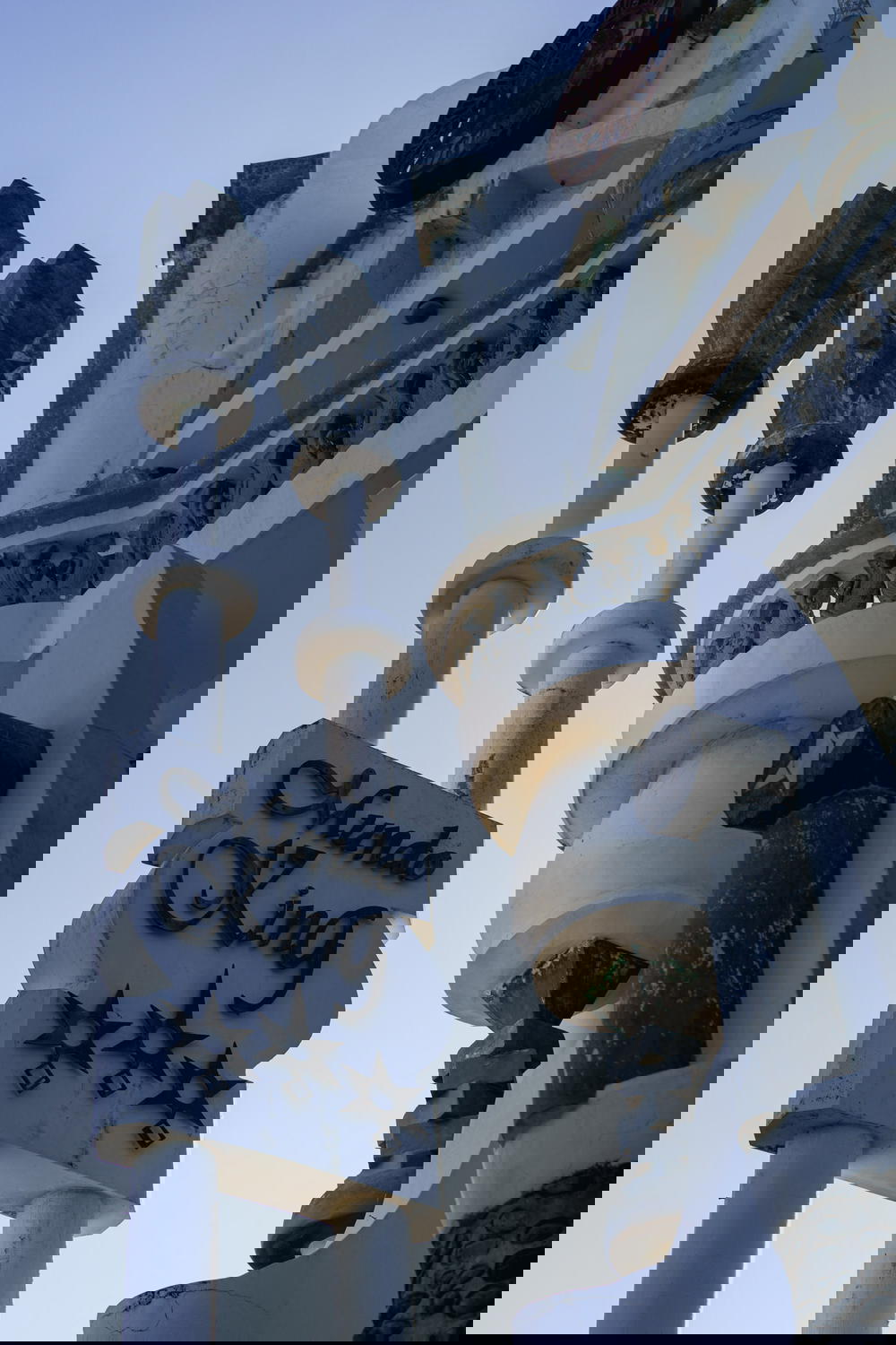 Mundo King sign on a white concrete pole against a blue sky 