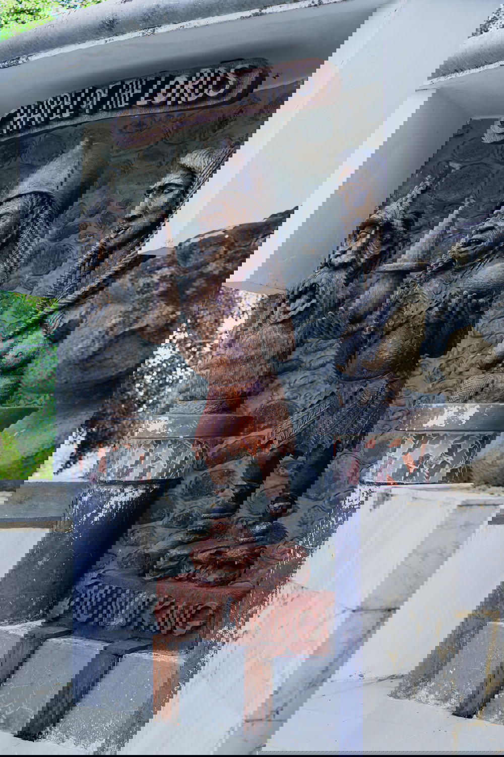 Wooden Chapel of the Lords sign with a wooden statue carved by Haitian artists and a stone wall