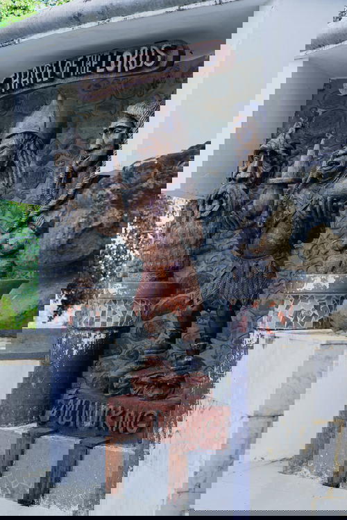 A statue of a king in front of a stone wall.