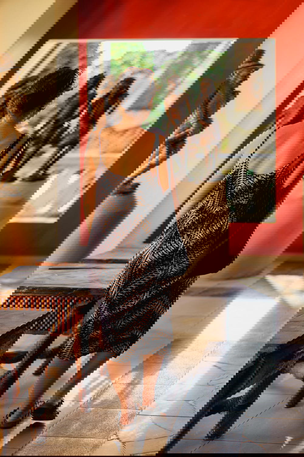 Girl in a dress walking in a hallway of Haitian wooden carving statues at Castillo Mundo King