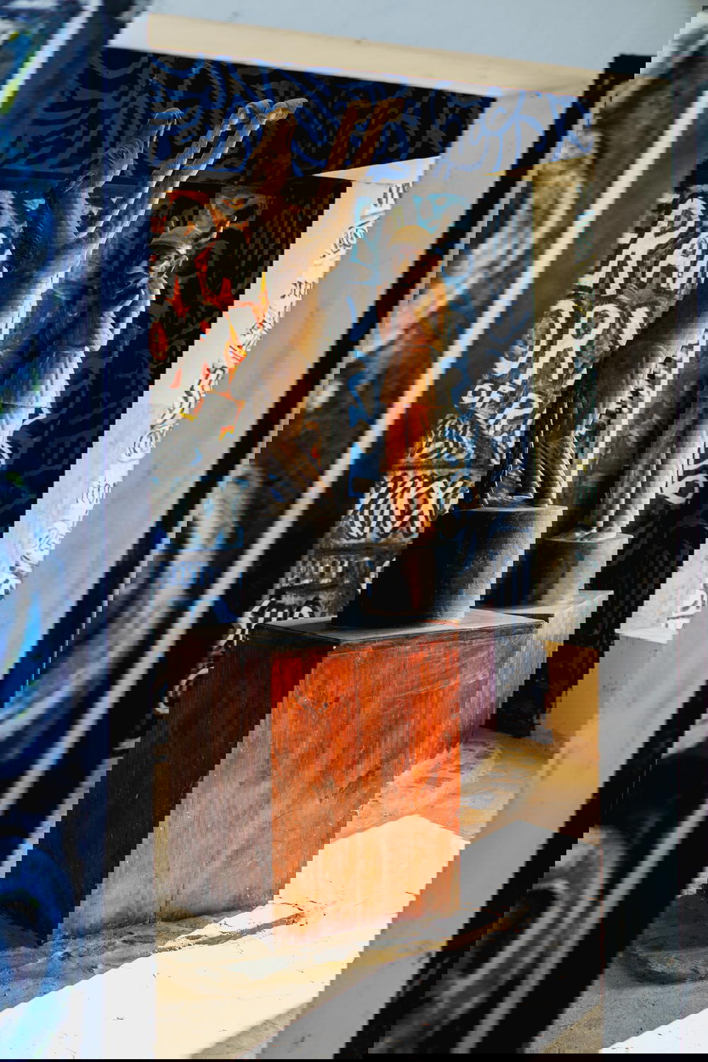 Wooden statues on pedestals in an open air room at Castillo Mundo King covered in wall art and hand painted murals