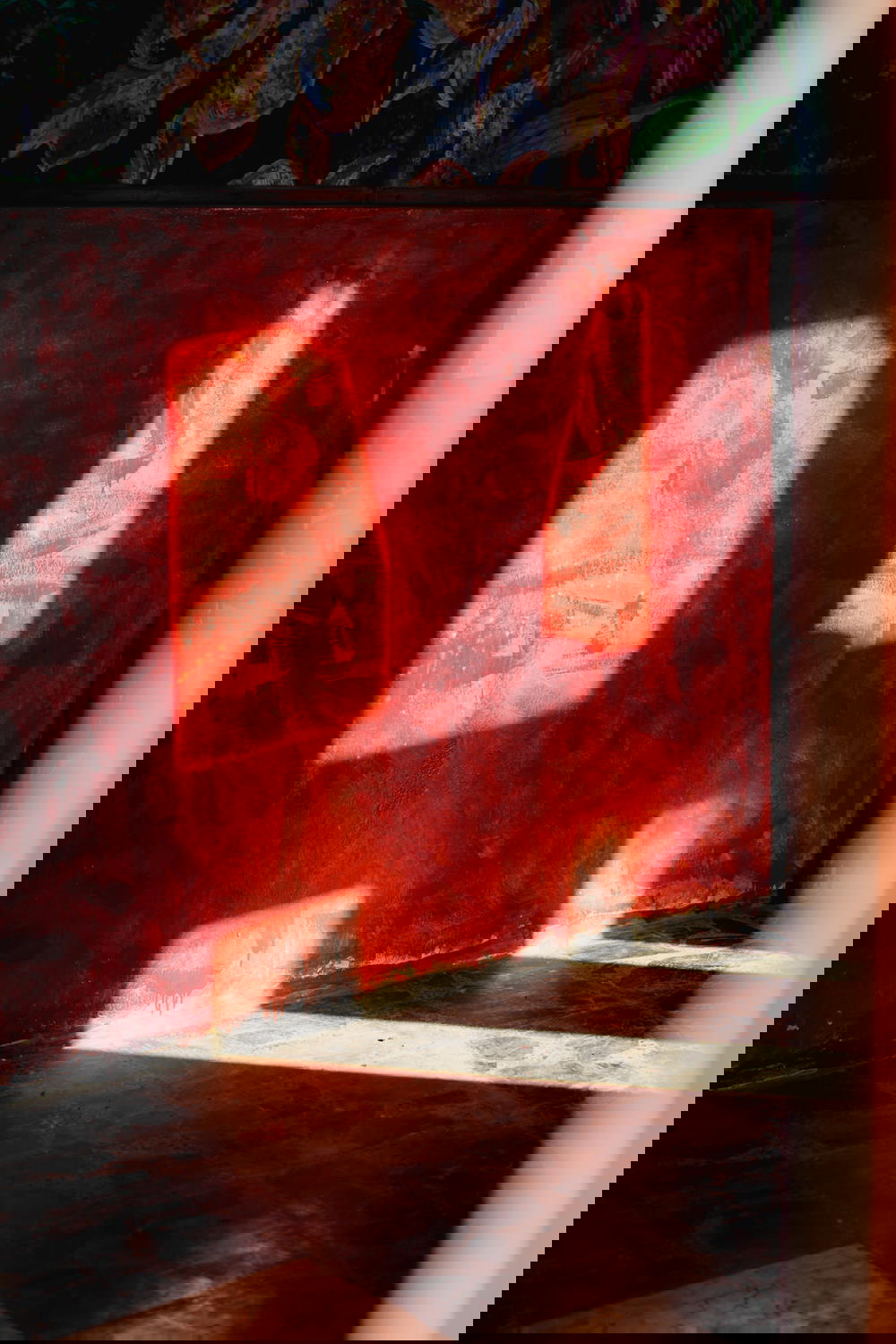 Shadows cast from light passing through concrete outlines against a red painted wall 