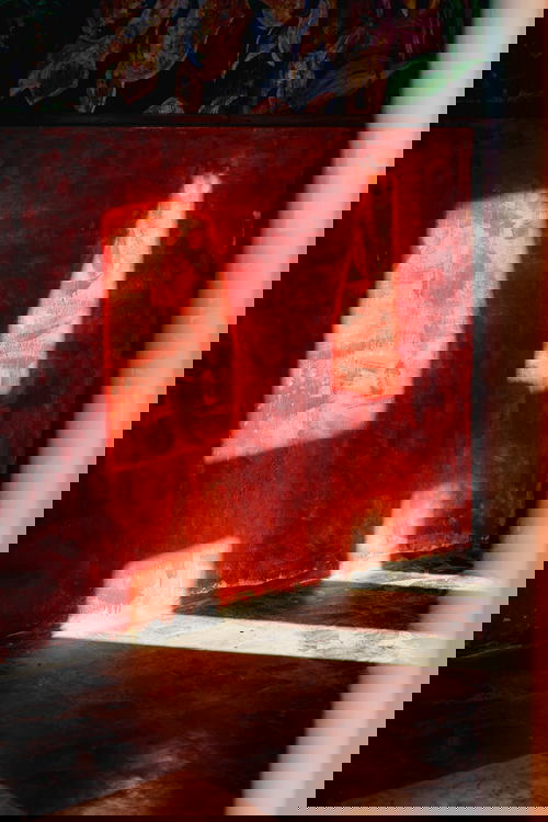 A person is sitting on a bench in a room with a red wall.