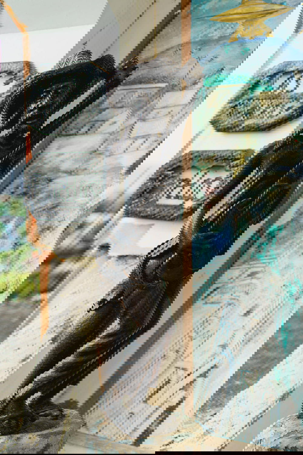 Black wooden Haitian sculpture of an old man with a guitar against white concrete on a balcony