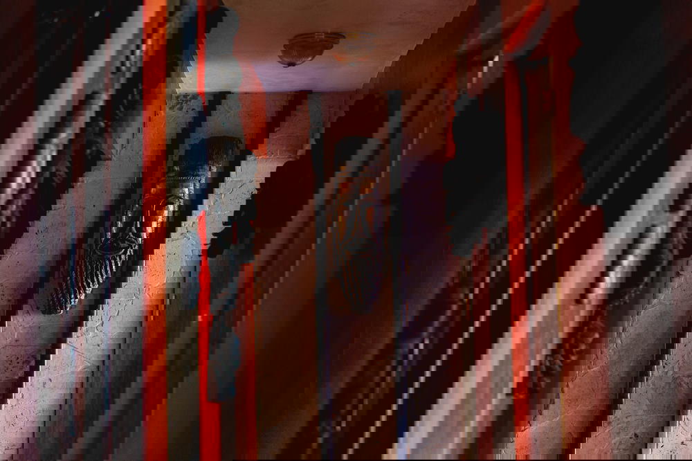 Haitian wooden carved mask at the end of a hallway lined with wooden carving masks