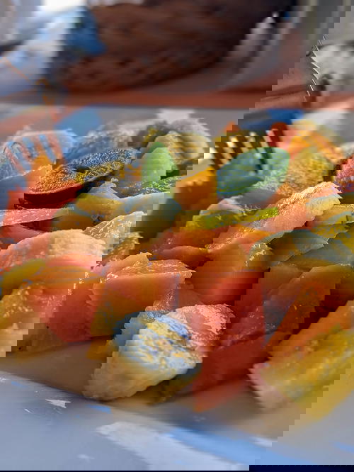Fruit salad of bananas, papaya, pineapple and lime on a white plate