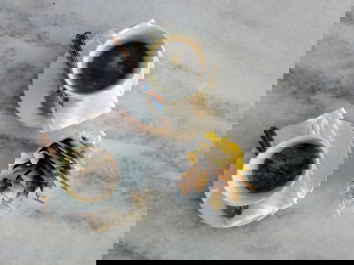 Two cups of black coffee on white saucers with two silver spoons