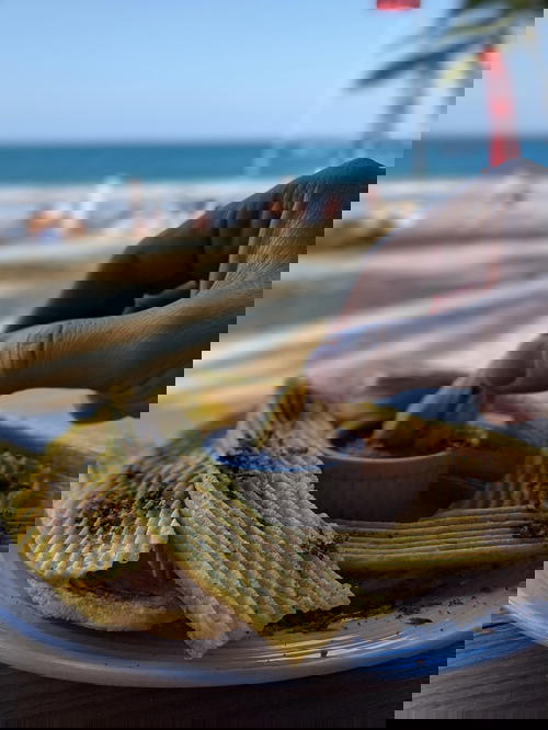 Fried long plantain slices served with bean dip at the beach