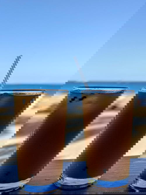 Two passionfruit juices in glasses on a wooden table at the beach